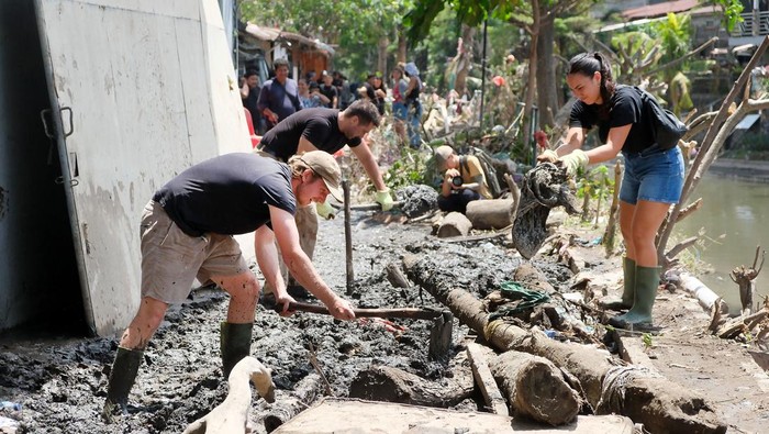Warga negara asing (WNA) membersihkan lumpur dan sampah akibat bencana banjir di kawasan Sungai Badung, Denpasar, Bali, Minggu (14/9/2025). Sebanyak 500 orang dari unsur TNI, Polri, aparatur sipil negara (ASN), dan masyarakat bersama-sama membersihkan sampah, lumpur, dan puing-puing bangunan akibat bencana banjir tersebut untuk mendukung optimalisasi upaya penanganan pasca bencana serta pemulihan kawasan yang terdampak. ANTARA FOTO/Nyoman Hendra Wibowo/bar