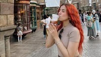 Momennya di Jepang juga terlihat dari foto ini. Ia menikmati minuman di Disneyland dan tampil stylish dengan rambut merah yang memikat perhatian. Foto: Instagram/@tasyafarasya