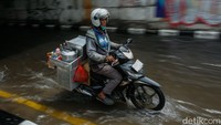 Genangan air memenuhi badan jalan hingga membuat sebagian pengendara memilih sisi kanan yang lebih cetek untuk bisa melintas.
