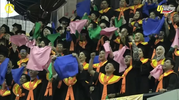 Wisudawan UI kibarkan bendera biru, pink, dan hijau saat momen Wisuda, Kamis (11/9/2025) lalu.