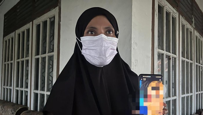 Dewi Yulianti, menunjukan foto luka lebam di bagian mata Dedi Putra yang ditemukan tewas di kamar rumahnya, di Muaro Jambi, Jambi