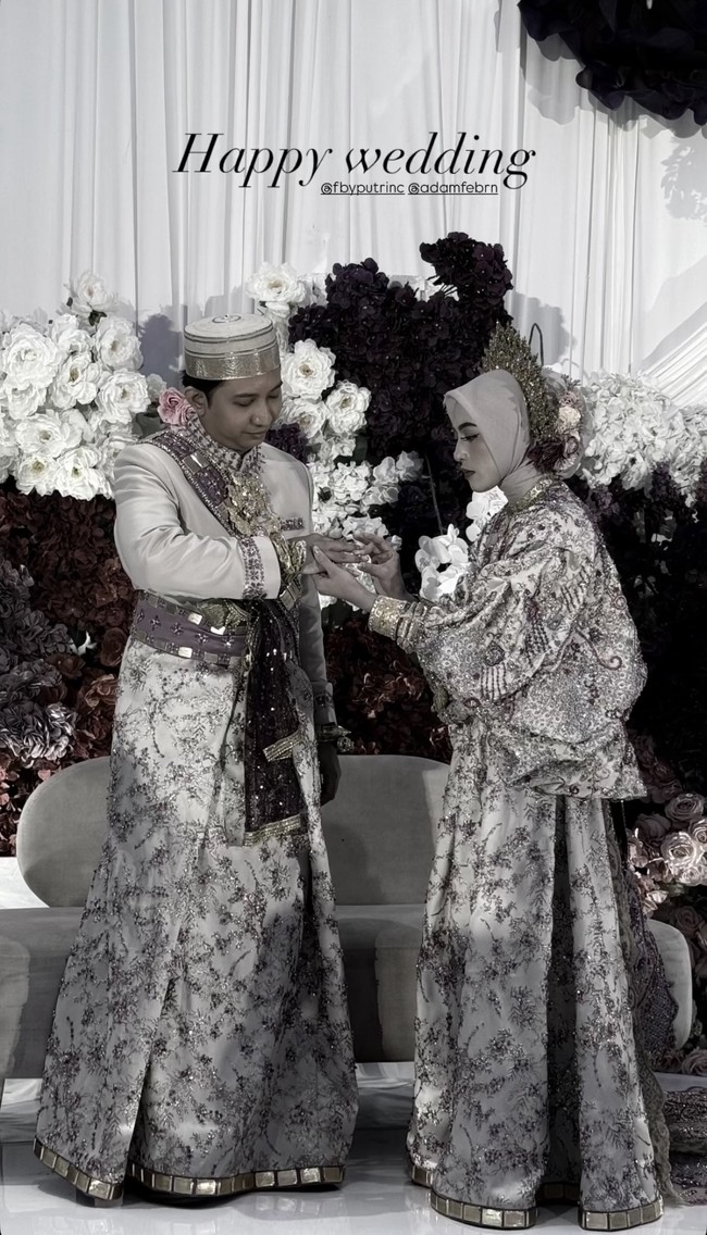 Dalam salah satu momen sakral, Adam terlihat memasangkan cincin ke jari manis Feby. Nuansa adat Bugis tampak begitu kental lewat pakaian berpotongan longgar dengan detail bordir penuh payet berkilau serta prosesi di acara pernikahan. Foto: Instagram/@fbyputrinc