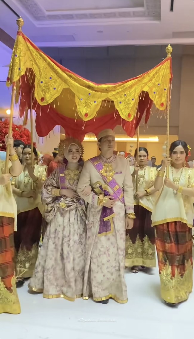 Feby dan Adam juga terlihat berjalan beriringan di bawah payung kuning emas yang dipegang para pengiring wanita dengan busana adat. Prosesi tersebut menegaskan kekentalan adat Bugis dalam pernikahan mereka. Foto: Instagram/@fbyputrinc