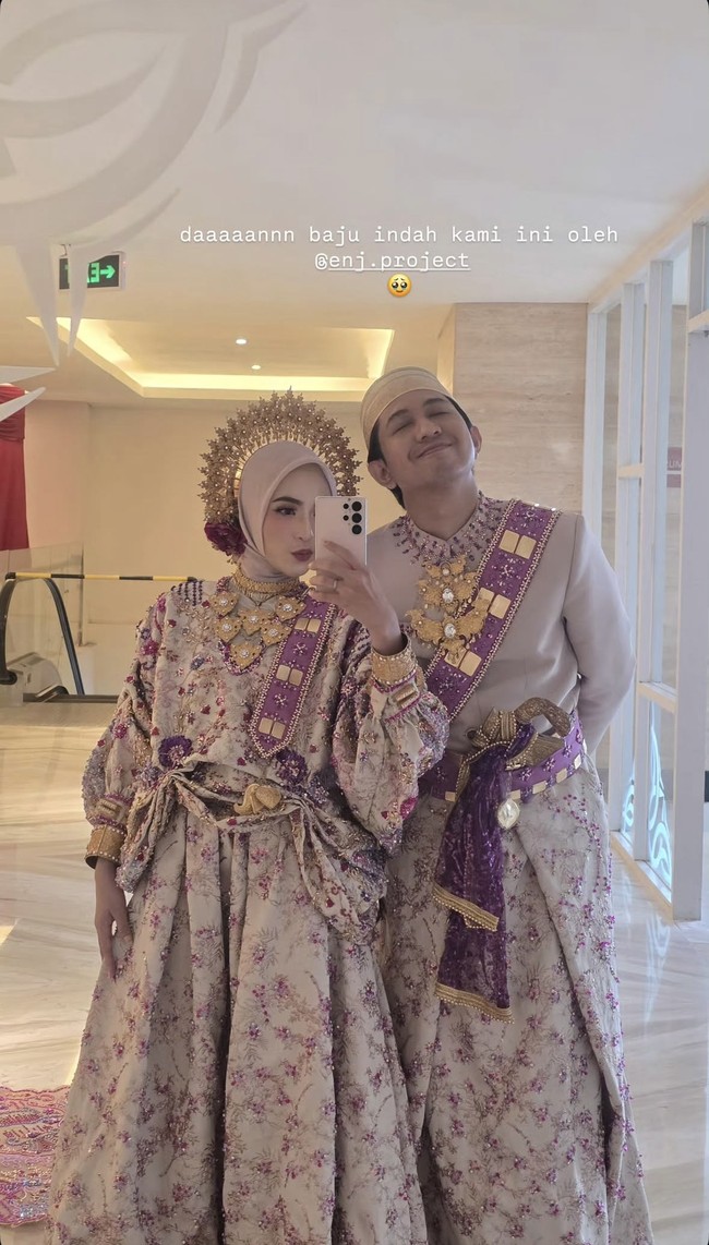 Diketahui busana adat yang dikenakan Feby dan Adam berasal dari Enj Project. Detail busana berupa kain bernuansa floral ungu-krem dengan aksen emas, serta selempang ungu berhias ornamen keemasan membuat penampilan keduanya terlihat memukau. Foto: Instagram/@fbyputrinc