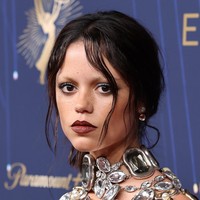 Rambut ditata rapi model kuncir kuda, mempertegas tampilan edgy yang makin dramatis dengan alis pirang pucat serta tulang pipi yang tajam. Sementara itu, bibirnya dipoles lipstik plum gelap yang menguatkan aura gothic khas Wednesday Addams, karakter yang diperankannya dalam serial Netflix populer, ‘Wednesday’. Foto: Getty Images/Amy Sussman