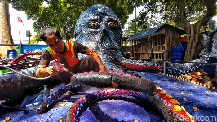 Kreasi Gurita Raksasa dari Botol Plastik, Ajak Warga Peduli Lingkungan Petugas Unit Penanganan Sampah (UPS) Menteng menyelesaikan detail tentakel gurita raksasa dari limbah plastik di Taman Sumenep, Jakarta, Senin (15/9/2025).