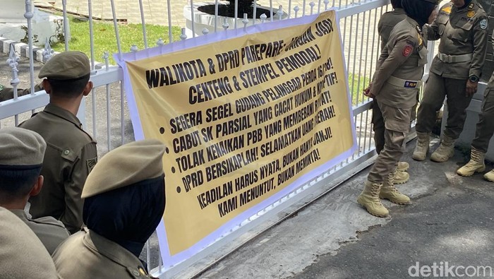 Sejumlah massa melakukan aksi demonstrasi di depan Kantor Wali Kota Parepare dan membentangkan spanduk di pagar dengan dijaga Satpol PP.