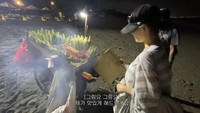 Di suatu malam, Seulgi jalan-jalan di sekitar area pantai. Ia membeli jagung bakar, juga mencoba membakar jagung itu layaknya si penjual. Foto: Instagram/YouTube Hi Seulgi