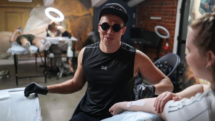 Igor Mikhaylov, a 38-year-old visually impaired tattoo artist, works on a tattoo reading 