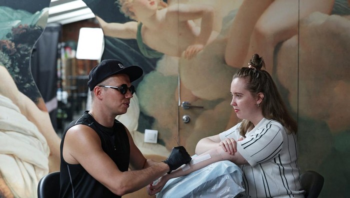 Igor Mikhaylov, a 38-year-old visually impaired tattoo artist, works on a tattoo reading 