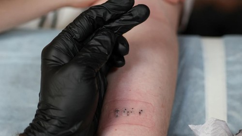 Igor Mikhaylov, a 38-year-old visually impaired tattoo artist, works on a tattoo reading 