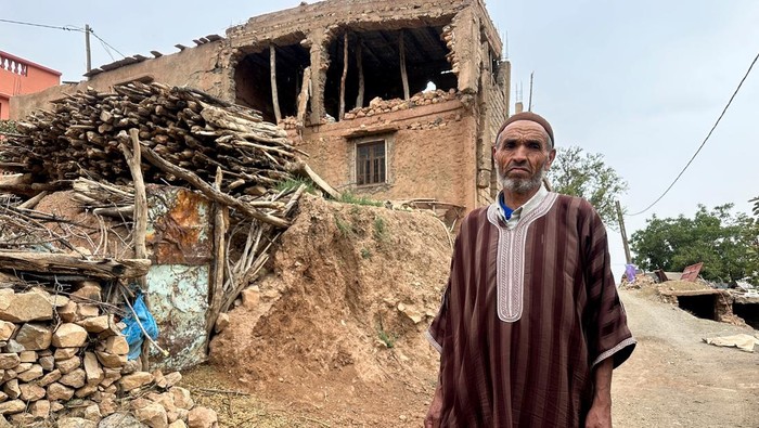 People stand in front of their makeshift shelter with a tin roof built by NGOs to house quake victims in Anerni village, Azgour, Morocco, September 6, 2025. REUTERS/Stringer