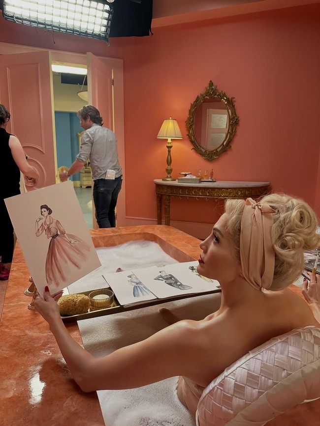 Wanita 56 tahun itu juga terlihat mengenakan jubah satin pink, seolah sedang bersiap untuk adegan di bathtub. Dalam foto lain, J.Lo tampak berpose di dalam bak mandi sambil menatap sketsa gaun di sebelahnya. Foto: Instagram/@jlo @lacarba