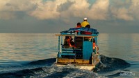 Pemandangan dari belakang perahu katinting yang mengangkut rombongan wisatawan, membelah ombak pagi.