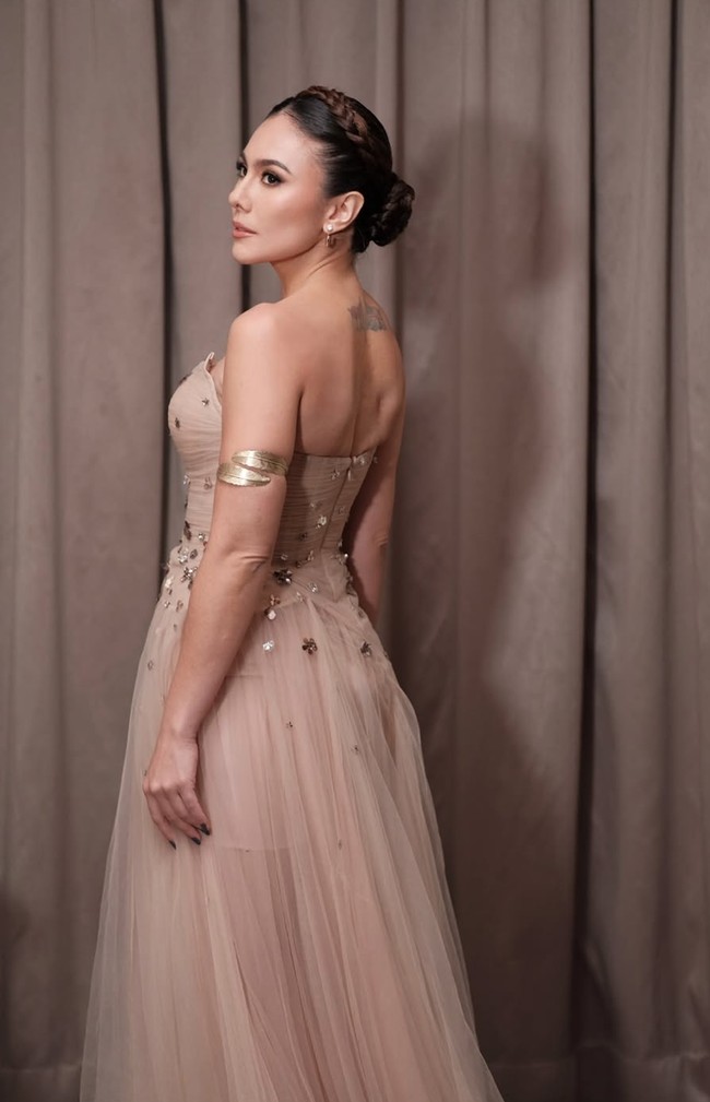 Potongan gaun yang terbuka di bagian belakang membuat tato berbentuk bendera di punggung Wulan jelas terlihat. Penampilan Wulan itu pun banjir pujian netizen. Tak sedikit yang ikut terpesona dengan kecantikannya. Beneran secantik itu mami, tulis salah satu komentar. Cantik nya lebihin anak muda ya ka wulan, komentar lain. Foto: Instagram/@wulanguritno