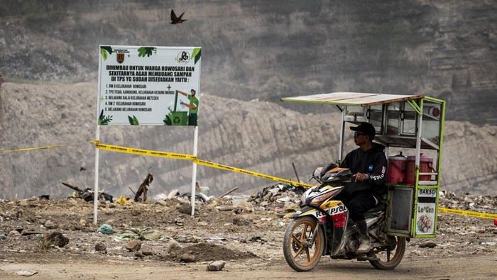 Pedagang melintas di dekat papan imbauan untuk tidak membuang sampah terpasang di tempat pembuangan akhir (TPA) ilegal, Rowosari, Semarang, Jawa Tengah, Rabu (17/9/2025). Pemkot Semarang menutup sekaligus menertibkan TPA ilegal yang berbatasan dengan Kabupaten Demak tersebut dikarena aktivitas yang tidak sesuai dengan regulasi serta mengganggu kenyamanan warga setempat akibat asap pembakaran sampah. ANTARA FOTO/Aprillio Akbar