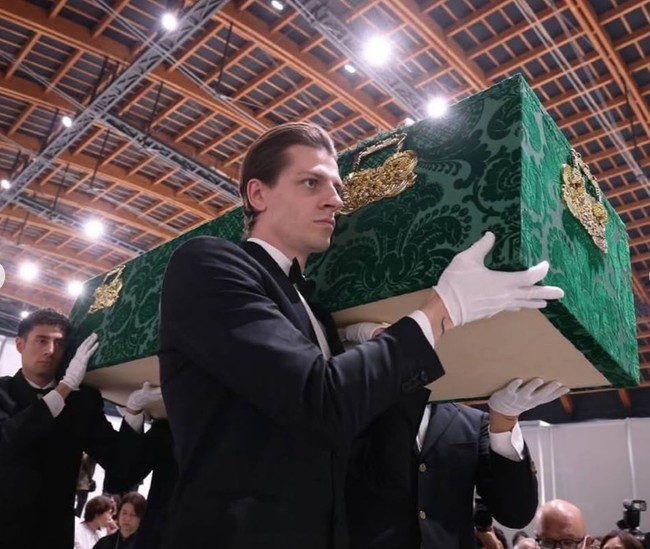 Di keterangan foto Dewi mengatakan bahwa peti matinya diangkat oleh 4 pria asing yang tampan. Peti mati hijau itu tampak mewah dengan perpaduan oranamen berwarna emas. Peti mati hijau saya dibawa oleh 4 pria asing yang tampan, dan bagian dalamnya dipenuhi gambar anjing peliharaan saya, tulis Dewi menggunakan aksara Jepang. Foto: Instagram/@dewisukarnoofficial