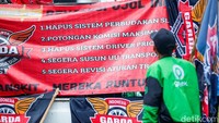 Spanduk dan poster berisi desakan pengaturan transportasi online dibentangkan para pengemudi Ojol di depan Gedung DPR.