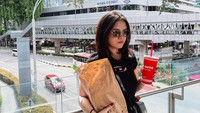 Momen kuliner lain dari Marsha Aruan di Singapura. Ia berpose di sebuah tempat dengan latar tempat gedung perkantoran sambil membawa sepaket burger dari Five Guys yang terkenal. Foto: Instagram/@aruanmarsha