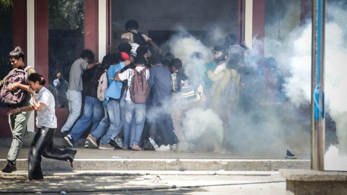 Students from several universities run from tear gas fired by police during their protest against the parliaments plan to purchase 65 SUVs for lawmakers at the National University of East Timor (UNTL) in Dili on September 15, 2025. (Photo by VALENTINO DARIELL DE SOUSA / AFP)