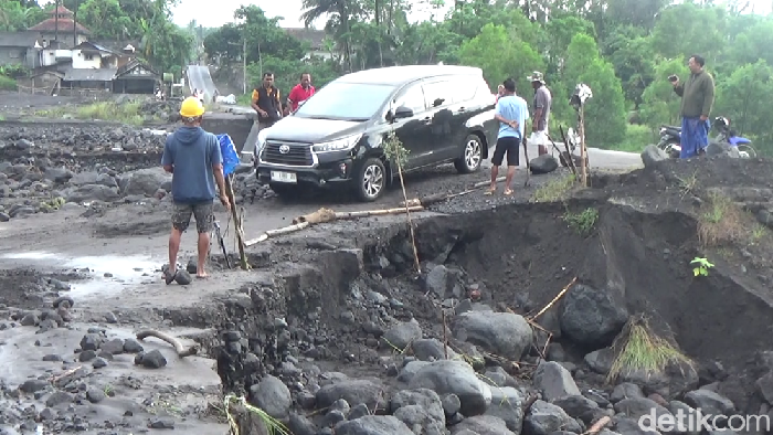 Kendaraan saat melintas di jalan yang terkikis banjir lahar di antarkecamatan Pasirian – Tempursari, Lumajang
