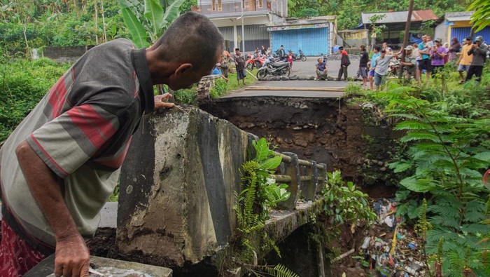 Jembatan putus akibat banjir di Lumajang Warga melihat kondisi jembatan yang putus di Desa Kandangtepus, Kecamatan Senduro, Lumajang, Jawa Timur, Jumat (19/9/2025). Jembatan berukuran 8x4 meter yang menjadi akses penghubung antar kecamatan itu putus akibat dinding penahan terkikis banjir dan telah diasesmen pihak terkait untuk proses penanganan. ANTARA FOTO/Irfan Sumanjaya/tom.