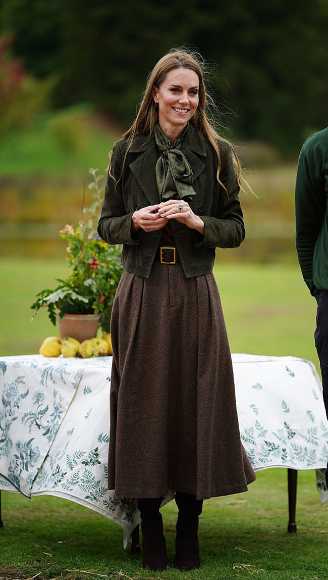 Seolah berada di frekuensi yang sama, Kate dan Melania kompak memilih jaket suede dengan nuansa warna musim gugur. Sang Putri Wales tampil dalam balutan cropped military jacket berwarna hijau zaitun dari Me + Em. Ia memadukannya dengan rok panjang tweed Evilyn Birdseye dari Ralph Lauren, dilengkapi belt kulit bertekstur croc dan syal sutra hijau. Foto: Getty Images/WPA Pool