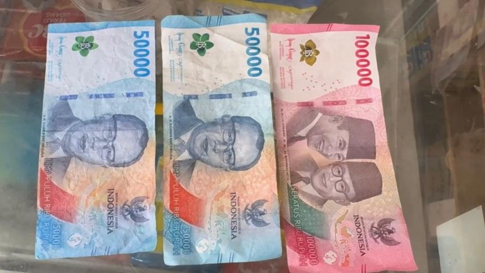 Penampakan perbandingan uang palsu (kiri) dan uang asli (tengah) yang diterima toko kelontong di Jambi
