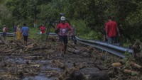 Seorang pesepeda mengangkat sepedanya melewati jalan yang tertutup material longsor di jalan lingkar, Ternate, Maluku Utara, Sabtu (20/9/2025). Foto: ANTARA FOTO/Andri Saputra