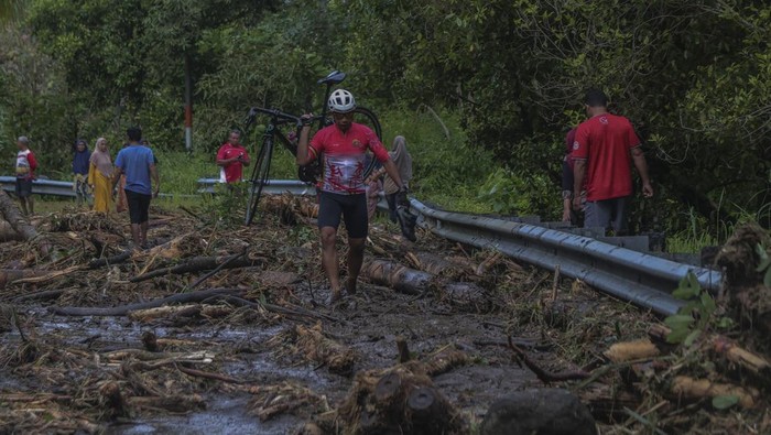 Sejumlah warga melihat material longsor yang menutupi jalan lingkar Ternate di Maluku Utara, Sabtu (20/9/2025). Curah hujan dengan intensitas tinggi pada Jumat (19/9) sore mengakibatkan jalan nasional yang menghubungkan Kelurahan Taduma dan Togafo itu tertutup material longsor dampak banjir dari Gunung Gamalama yang melewati jalur kali mati sehingga jalan lingkar pulau Ternate tidak bisa dilewati untuk sementara. ANTARA FOTO/Andri Saputra/rwa.