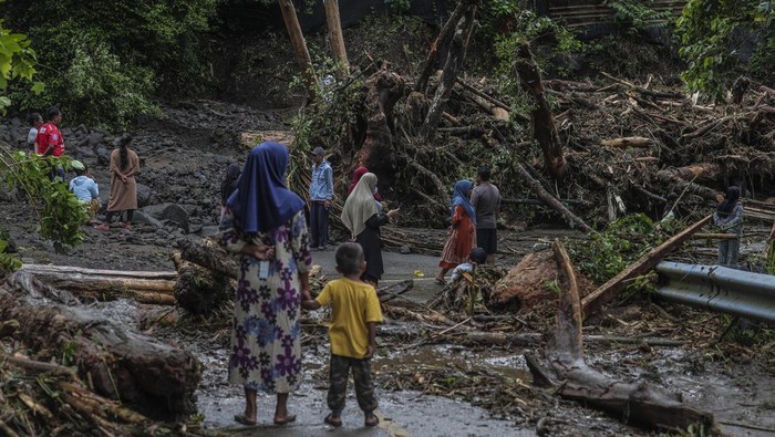 Jalan tertutup material longsor dampak banjir di Ternate Sejumlah warga melihat material longsor yang menutupi jalan lingkar Ternate di Maluku Utara, Sabtu (20/9/2025). Curah hujan dengan intensitas tinggi pada Jumat (19/9) sore mengakibatkan jalan nasional yang menghubungkan Kelurahan Taduma dan Togafo itu tertutup material longsor dampak banjir dari Gunung Gamalama yang melewati jalur kali mati sehingga jalan lingkar pulau Ternate tidak bisa dilewati untuk sementara. ANTARA FOTO/Andri Saputra/rwa.