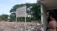 Seorang warga sedang melihat rumah milik tentangganya yang lebih dulu dibongkar oleh Pemkot Surabaya.