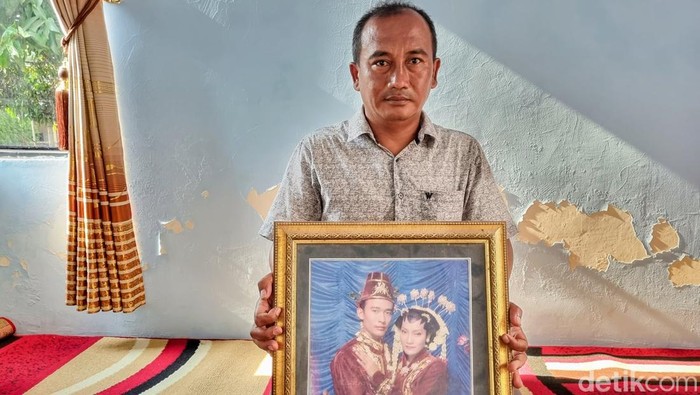 Rohmat saat menunjukkan foto pernikahan korban bersama istrinya