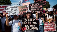 Para demonstran membawa spanduk dan poster yang menuding adanya penyalahgunaan anggaran serta kurangnya transparansi dalam proyek pengendalian banjir yang seharusnya memberi perlindungan bagi warga. REUTERS/Lisa Marie David