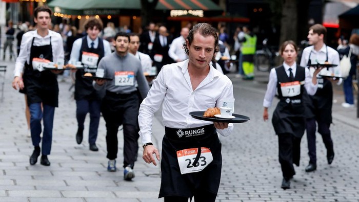 Jalanan Paris, Prancis, dipenuhi keriuhan dan tawa saat para pelayan kafe mengikuti Cafe Race 2025, Sabtu (21/9/2025). Dalam perlombaan legendaris ini, peserta ditantang untuk berlari sambil membawa nampan berisi secangkir kopi, croissant, dan segelas air tanpa menumpahkan isinya. REUTERS/Stephanie Lecocq