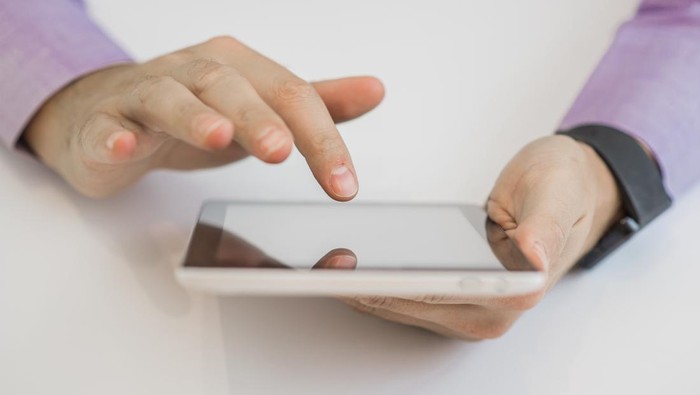 Cropped image of handsome young businessman using a tablet and smiling while working
