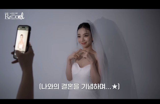 “Aku harus mengirimnya ke ibuku. Ibu aku menikah hari ini,” ujarnya sebelum meminta bantuan staff mengabadikan fotonya dalam balutan gaun pengantin. Foto: dok. SM Entertainment