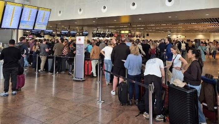 Passengers wait as they queue up at a check-in area of Brussels Airport in Brussels on September 20, 2025, after the airports system was hit by a cyberattack overnight on September 19. Major European airports including Brussels, Berlin and Londons Heathrow were hit by cyber-related disruption on September 20 affecting automated check-in and baggage drop systems and causing delays. We have become aware of a cyber-related disruption to our MUSE software in select airports, airport service provider Collins Aerospace said. (Photo by Joris SMETS / Belga / AFP) / Belgium OUT