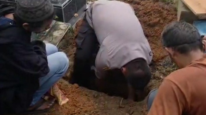 Polisi saat membantu pemakaman jasad bayi dari pasutri tunawisma di Palembang.