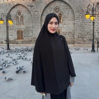 Dengan latar Masjid Ghamamah di Madinah dan kawanan burung merpati, Angbeen terlihat menawan dalam hijab syari hitam polos yang menonjolkan sisi anggun. Foto: Dok. Instagram/@angbeenrishi.
