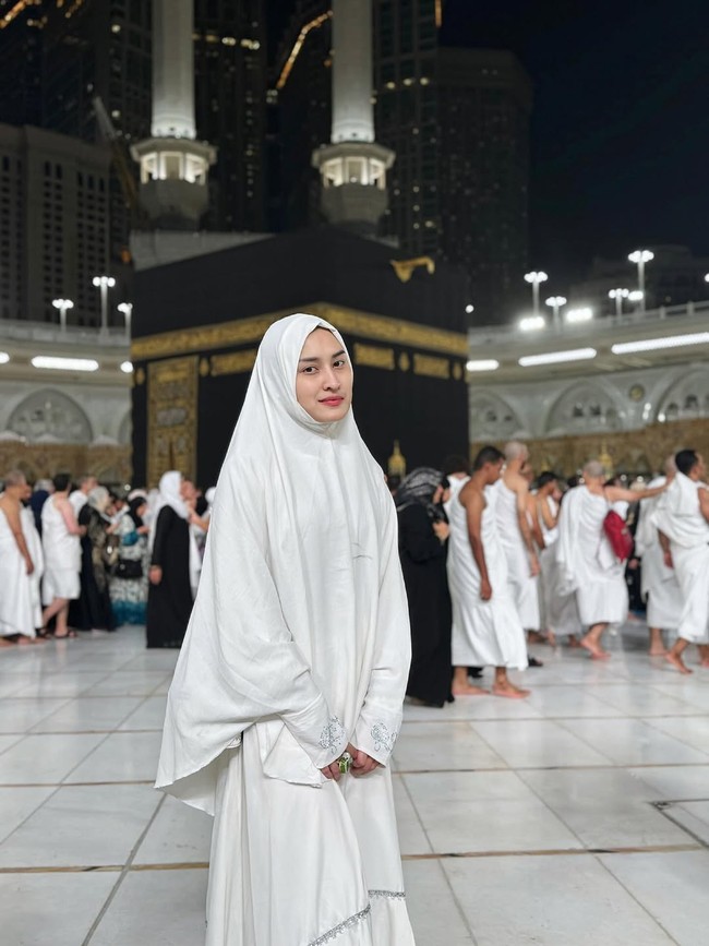 Dengan balutan hijab syari dan abaya putih, Angbeen mengabadikan momen saat di depan Ka’bah. Angbeen terlihat menjalani ibadah umrah tanpa didampingi oleh suaminya, Adly Fairuz. Foto: Dok. Instagram/@angbeenrishi.