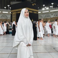 Dengan balutan hijab syari dan abaya putih, Angbeen mengabadikan momen saat di depan Ka’bah. Angbeen terlihat menjalani ibadah umrah tanpa didampingi oleh suaminya, Adly Fairuz. Foto: Dok. Instagram/@angbeenrishi.