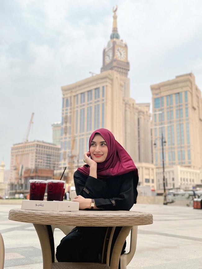 Wanita kelahiran 27 Agustus 1997 itu tampil berbeda dengan hijab merah marun saat bersantai di kafe dekat Menara Abraj Al-Bait, Mekkah. Foto: Dok. Instagram/@angbeenrishi.