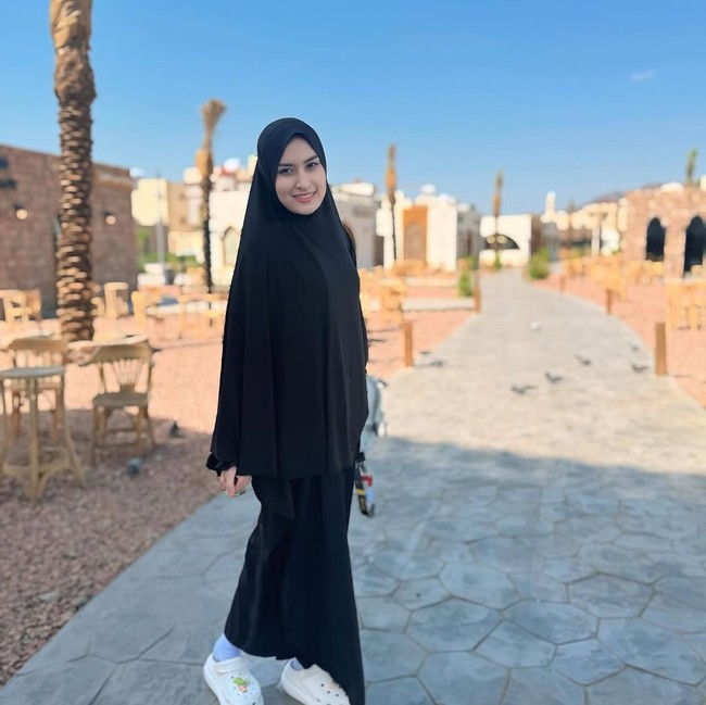 Wajah tanpa pulasan makeup, pemain film Kala Sinta Berburu Cinta itu memadukan khimar dan abaya hitam dengan sneakers putih saat berpose di area terbuka, memberikan kesan modern dan segar. Foto: Dok. Instagram/@angbeenrishi.