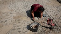 Seorang pekerja memeriksa bagian mosaik yang memuat prasasti kuno, menyingkap jejak sejarah kekuasaan Bizantium di Dardania. Sementara Theodora, permaisuri Justinianus yang berasal dari latar belakang sederhana, merupakan sosok cerdas, berpengaruh, dan berani. Ia dikenal memperjuangkan hak perempuan, termasuk perlindungan dari perdagangan manusia, hak kepemilikan, dan perceraian. Foto: REUTERS/Valdrin Xhemaj