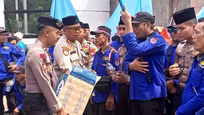 Polisi membagikan air mineral dan roti kepada massa demo di DPR, Senin (22/9/2025).