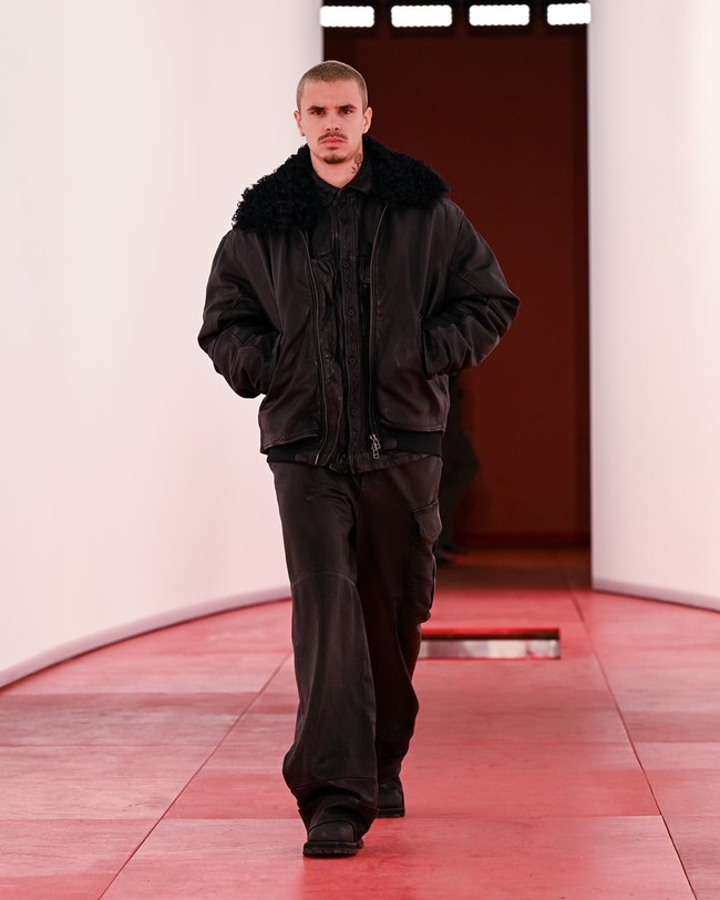 Romeo Beckham, anak kedua David Beckham dan Victoria Beckham, debut di London Fashion Week untuk koleksi Fall/Winter 2025. Pria yang sempat menjajal dunia sepakbola ini tampil mengenakan busana serba hitam dengan padanan jaker parka, kemeja dan celana. Foto: Instagram/@hm