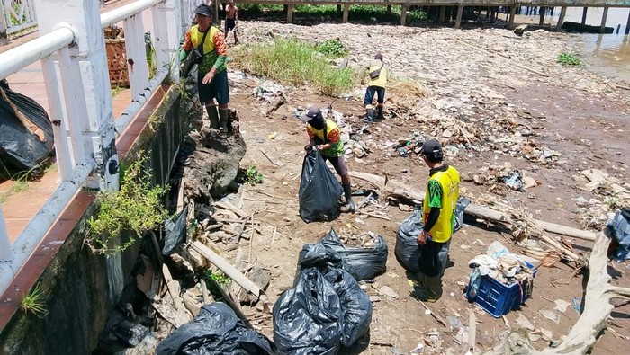 Petugas DLH membersihkan tumpukan sampah di Kampung Kapitan Palembang.