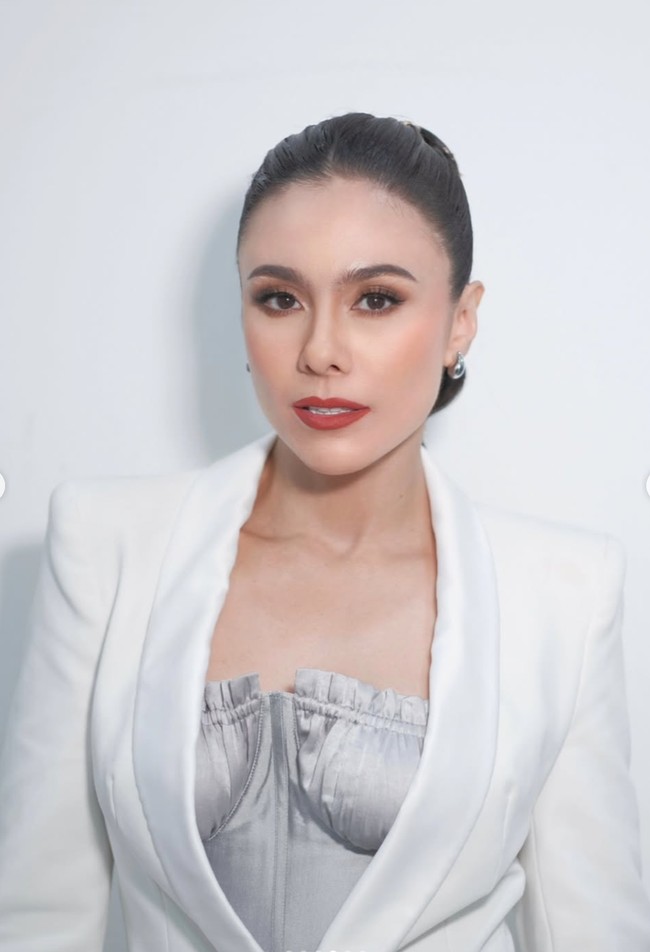 Makeup Wulan sangat elegan dengan fokus pada complexion flawless, riasan mata smokey tipis, dan bibir merah klasik yang menonjolkan kesan anggun. Sementara rambutnya ditata ponytail panjang dengan detail kepangan berlapis yang dihias aksen keemasan, memberikan efek mewah dan artistik. Foto: Instagram/@wulanguritno/@masayuanastasia