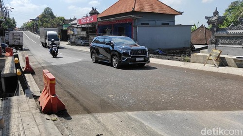 Kendaraan sudah melintasi jalan raya Lukluk, Mengwi, Badung yang belum diaspal, Selasa (23/9/2025). (Agus Eka/detikBali)